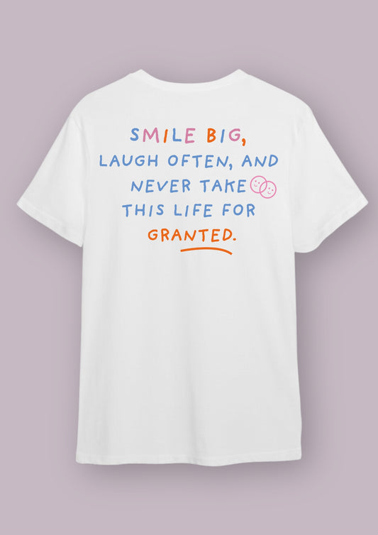 T-shirt blanc avec la phrase "smile big, laugh often, and never take this life for granted". Cette phrase est écrite en bleue, rose et orange.